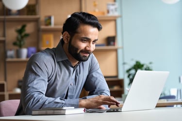 Man using a laptop to write a self-evaluation for 360 feedback provided by his HR leadership