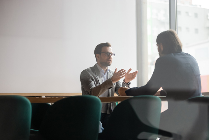 Man in glasses using 360 degree feedback to help improve a leadership team member's performance and mitigate derailment